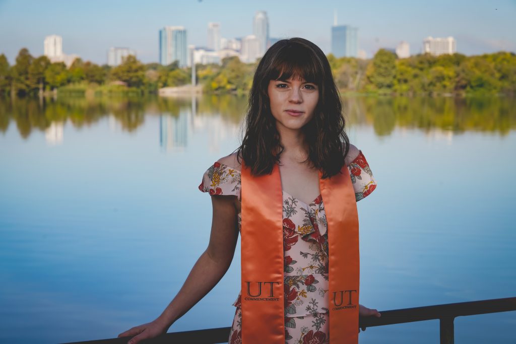 College senior wearing a UT commencement stole in front of the Austin skyline College senior wearing a UT commencement stole in front of the Austin skyline